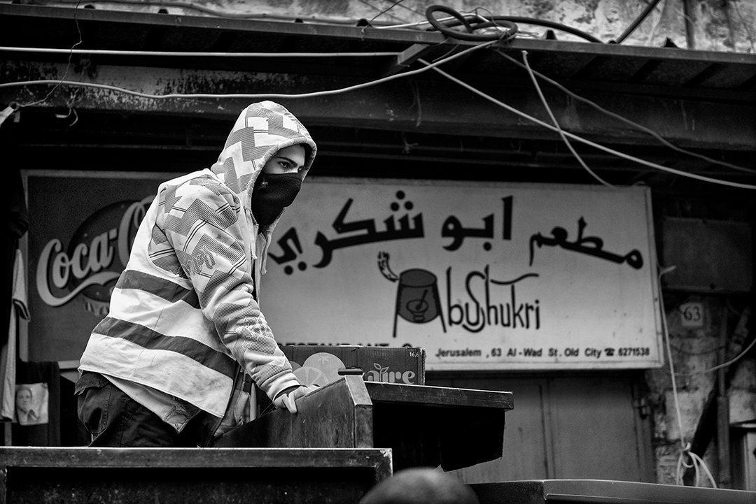 A person wearing a striped garment in front of a shop.